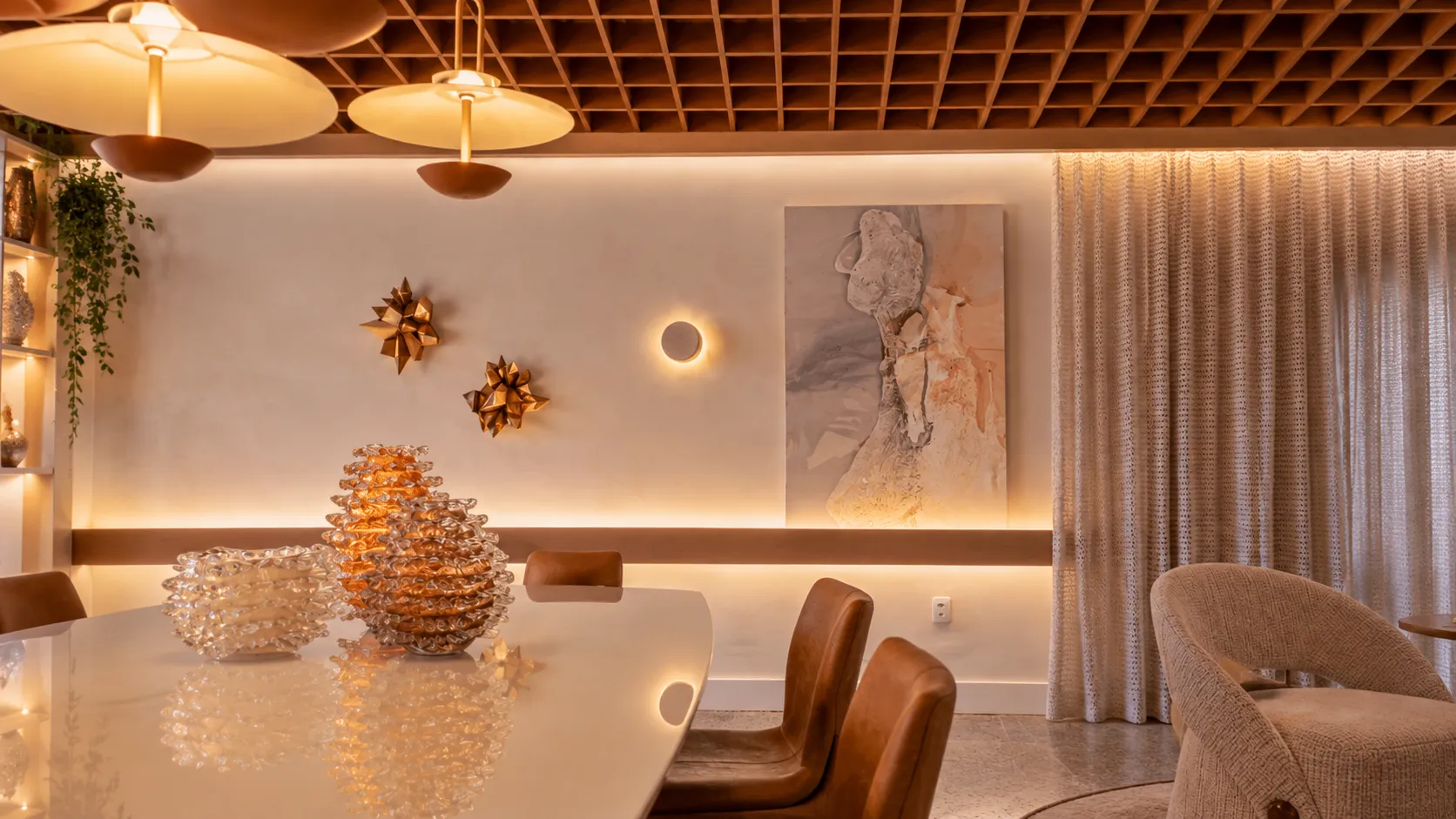 Mesa de jantar com peças âmbar e luminárias em tom quente